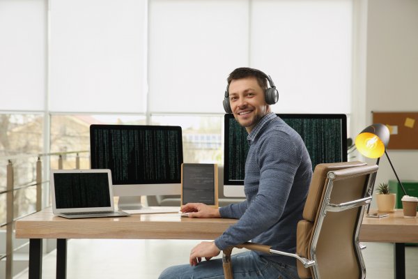 Guy smiling at his computer with headphones on 